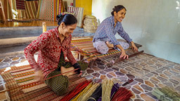These women weave straw mats, some used for sleeping rather than mattresses.  Their business is in the front of their house on a tiny street (sidewalk almost) and they live in a lovely area which starts just behind the stacked mats.