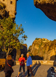 One monastery looming over us, another in the distance under the morning moon and yellow sunlight.